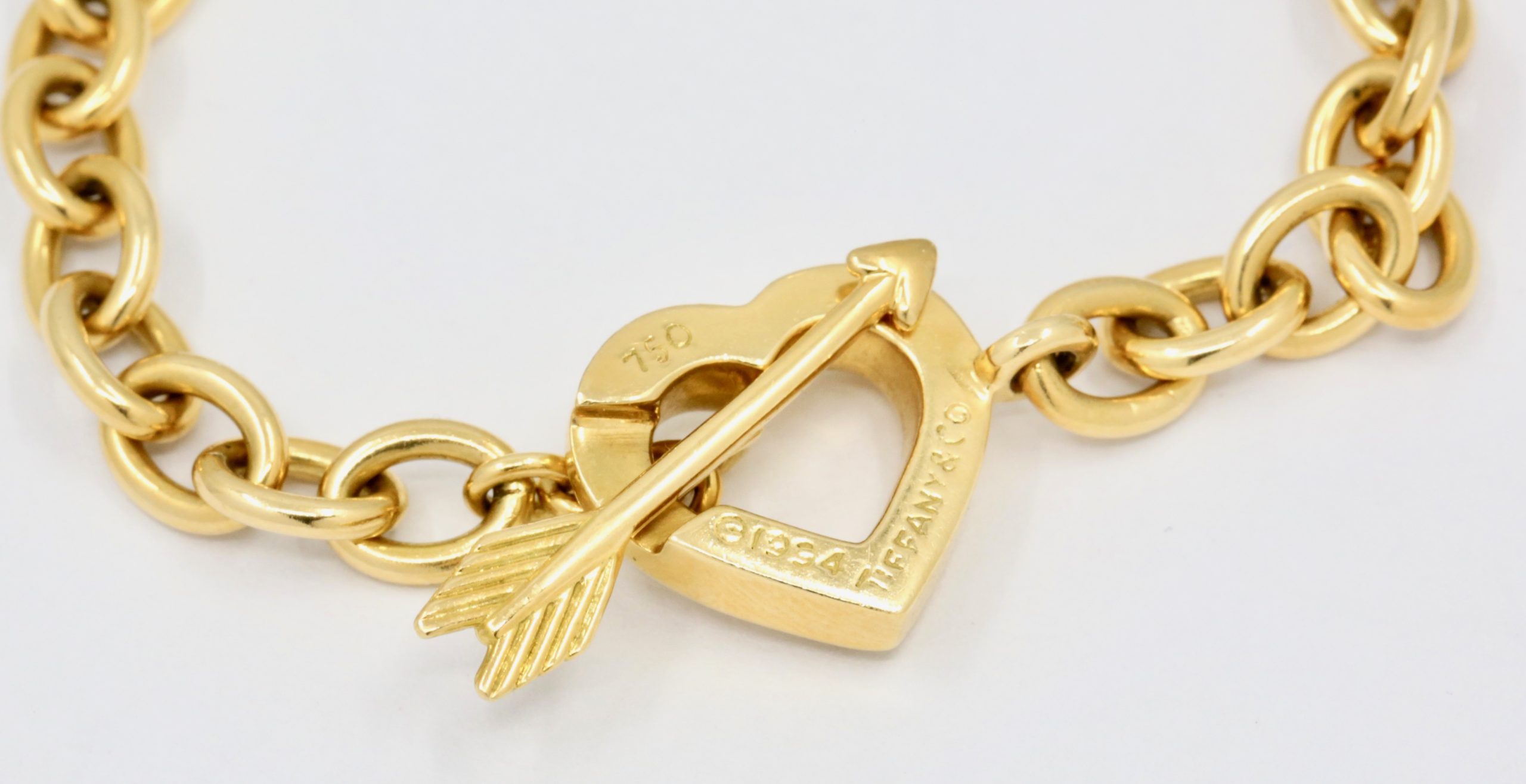 Tiffany & Co. Bracelet, Heart‑shaped clasp with an arrow toggle that passes through the heart. Interlocking oval chain links in 18ct Yellow gold. Stamped Tiffany & Co. 750 (gold)